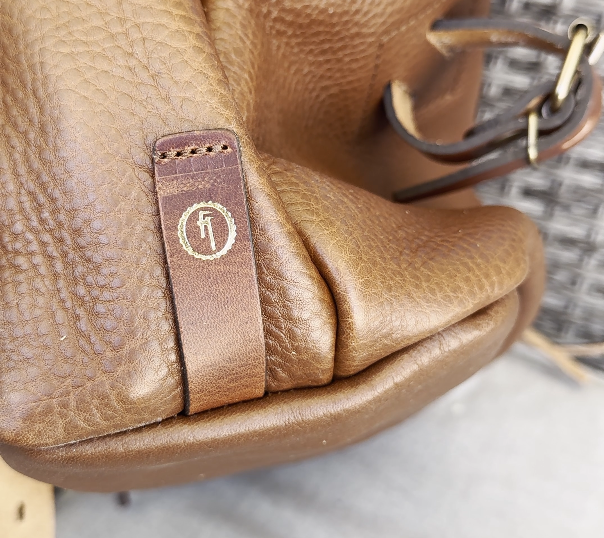 Gold foil stamp on leather strip attached to backpack