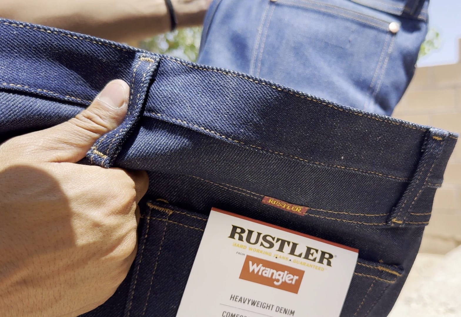 Holding a new pair of Rustler jeans in front of Wrangler 13MWZ