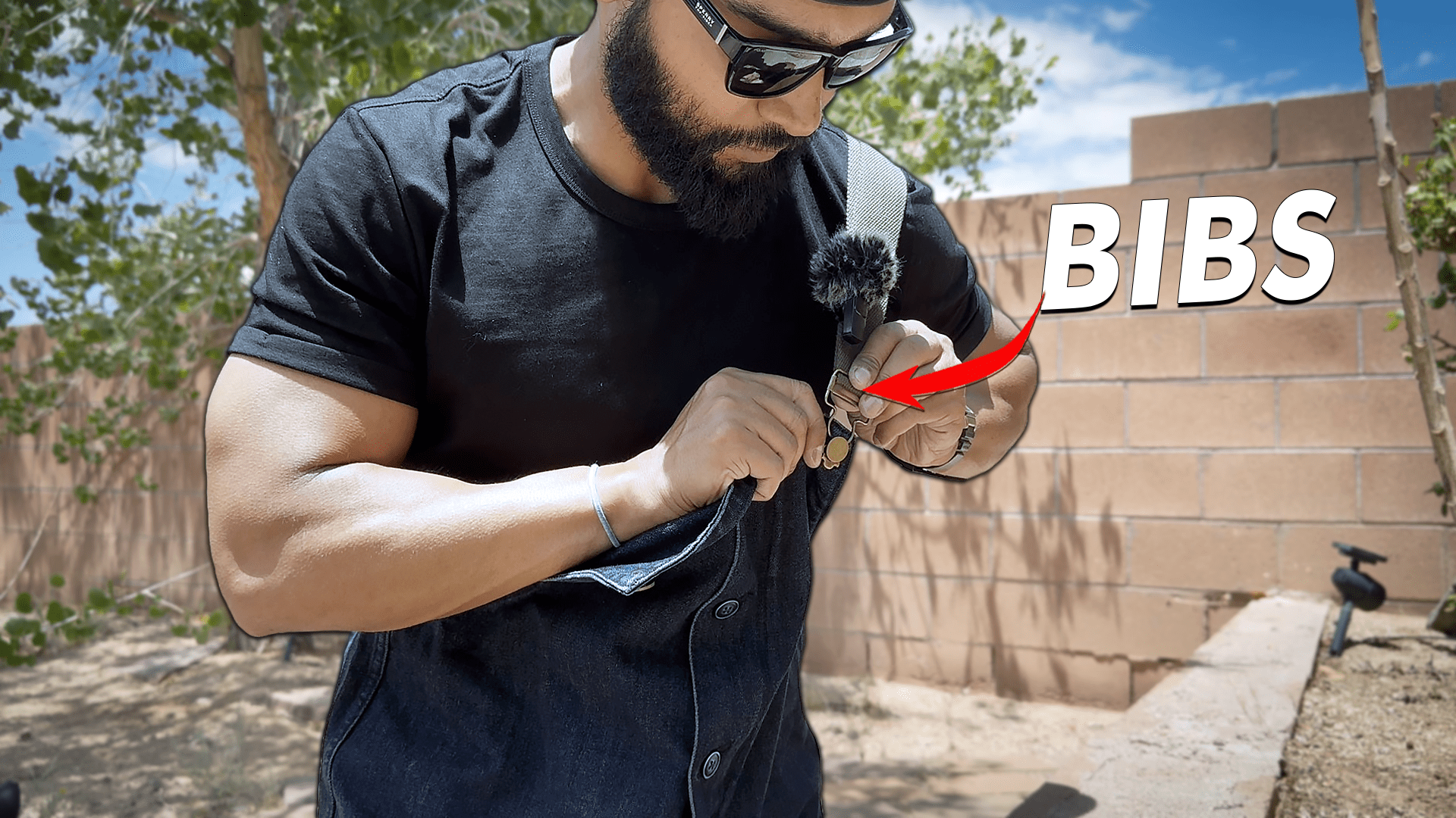 Undoing the brass hook on a pair of denim overalls