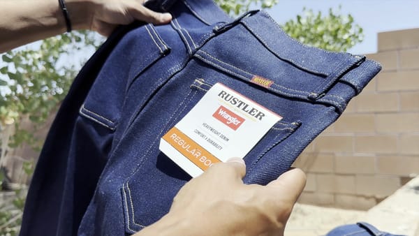 Holding a new pair of Rustler from Wrangler Regular Boot Cut Jeans in the Rigid Variant